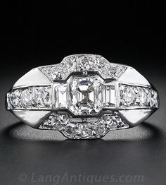 an antique diamond ring on a black surface with diamonds around the band and sidestones