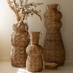 three wicker vases with flowers in them sitting on a table next to a wall