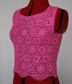 a pink crocheted top on a mannequin with a black belt around the waist