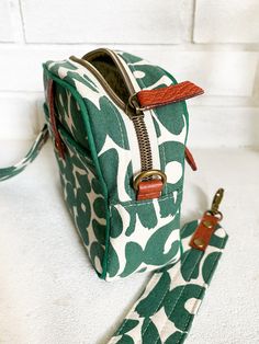 a green and white floral print purse with a matching lanyard is on the floor