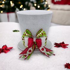 a white top hat with red and green bows on it sitting next to christmas decorations