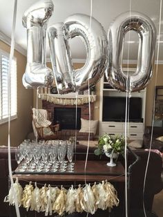 balloons and streamers are hanging from the ceiling in front of a table with wine glasses