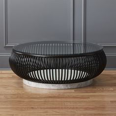 a black and white coffee table sitting on top of a hard wood floor next to a gray wall