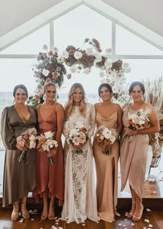 a group of women standing next to each other in front of a white and brown arch