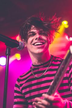 a young man holding a guitar in front of a microphone