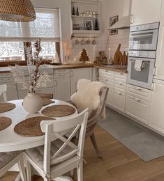 a kitchen with white cabinets and wooden floors is pictured in this image, there are four chairs around the table