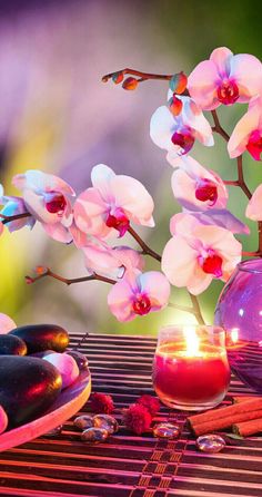 a vase filled with pink flowers next to a candle and donut on a table