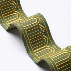 a roll of green and gold ribbon on a white surface with lines in the middle