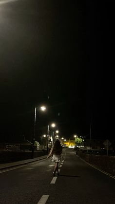 a person riding a skateboard down the middle of an empty street at night time