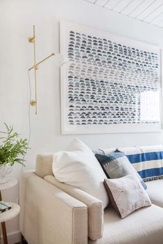 a living room with white couches and blue pillows on the back of the couch