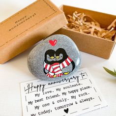 a rock with a penguin painted on it next to a box of love note cards