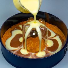 a person pouring sauce on top of a cake in a blue pan with white icing