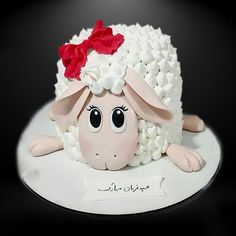 a cake made to look like a sheep with a red bow on its head