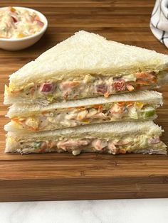 a sandwich cut in half sitting on top of a cutting board next to a bowl