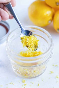 a spoon with some food in it on top of a glass jar next to lemons