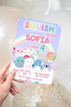 someone holding up a squish on over softa birthday party card in front of some balloons