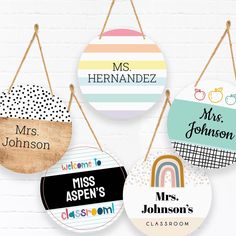 four personalized hanging signs are hung on a brick wall, each with different colors and designs