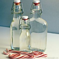 three empty glass bottles sitting next to each other on a white counter top with candy canes