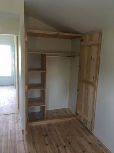 an empty room with wood floors and open closet doors