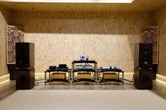 an empty room with speakers and tables in the center, on carpeted flooring