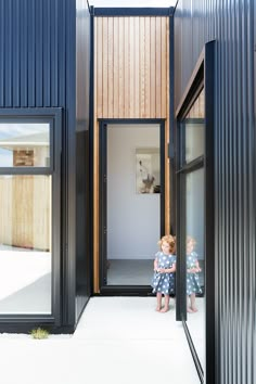 two children are sitting in the doorways of a house that is made out of corrugated