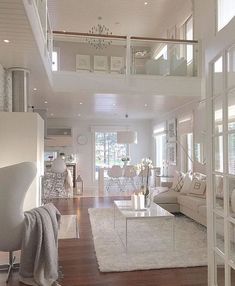 a living room filled with white furniture and lots of windows on top of the walls