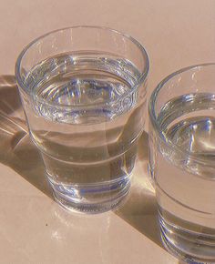 two glasses filled with water sitting on top of a table