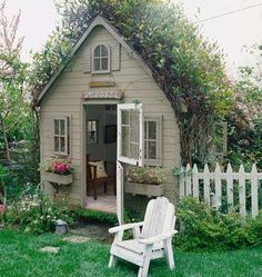 a white chair sitting in front of a small house with a garden on the lawn