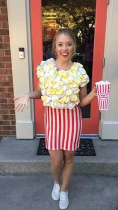 a woman standing in front of a red door holding two popcorn buckets with both hands