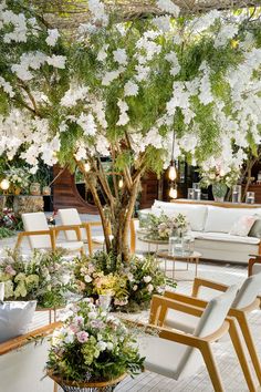 a room filled with lots of white furniture and flowers on the tree in front of it