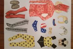 paper doll clothes and accessories laid out on a table