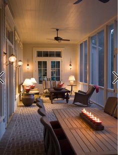 a long table with candles on it sitting in front of some chairs and windows next to a door