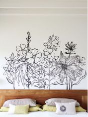 a bed with white sheets and pillows in front of a flower mural on the wall