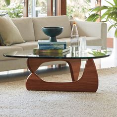 a living room with a couch, coffee table and books on the floor in front of a window