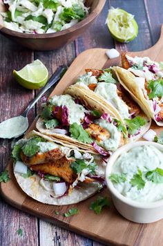 fish tacos with guacamole and salsa on a cutting board