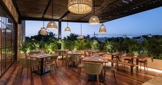 an outdoor dining area with wooden tables, chairs and hanging lights on the outside wall