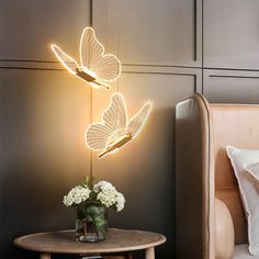 a bed room with a lamp that has two butterflies on it and a table next to it