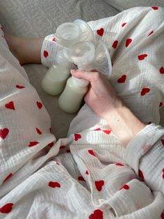 a person laying in bed with two baby bottles