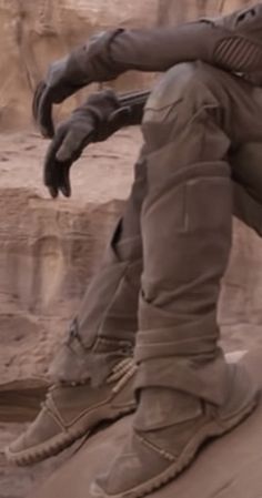 a close up of a person sitting on top of a rock with his foot in the air