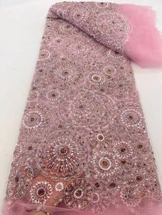 a pink scarf with sequins on it sitting on top of a white table