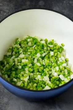 chopped green onions in a blue bowl on a counter top, ready to be cooked