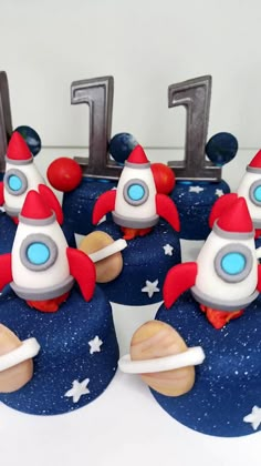 some cupcakes are shaped like rockets on top of stars and the number one is made out of fondant