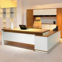 an office desk with a laptop on it in front of a book shelf and cabinets