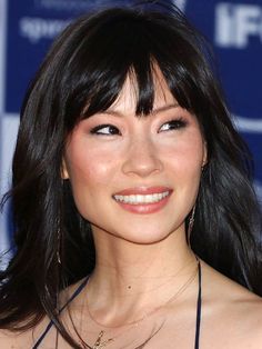 a close up of a person wearing a necklace and smiling at the camera with her eyes wide open