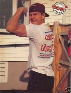 a young man posing for a photo in front of a house with his arm up