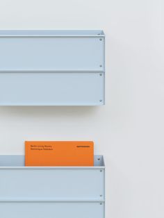 an orange folder sitting on top of a blue shelf next to another white wall mounted object