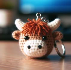 a crocheted cow keychain is sitting on a table