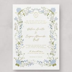 a wedding card with blue flowers and greenery on the front, in gold foil