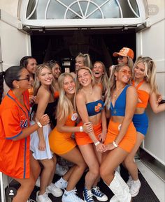 a group of young women standing next to each other in front of a door wearing orange and blue outfits