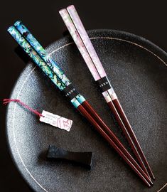 three chopsticks are sitting on a black plate